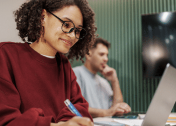 Estudante se preparando para concurso público com anotações e notebook em ambiente de estudos.