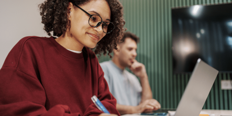 Estudante se preparando para concurso público com anotações e notebook em ambiente de estudos.