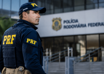 Policial rodoviário federal de costas observa a entrada de um prédio da Polícia Rodoviária Federal