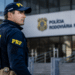 Policial rodoviário federal de costas observa a entrada de um prédio da Polícia Rodoviária Federal