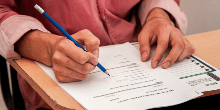Pessoa preenchendo formulário de concurso público em carteira escolar, representando inscrições abertas para o Concurso Unificado no Piauí.