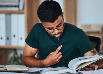 Candidato estudando para concursos públicos com livros e materiais de preparação.