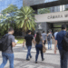 Candidatos caminham em direção a uma Câmara Municipal para participar de concurso público.