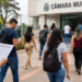 Pessoas chegando à Câmara Municipal para participar de concurso público com documentos em mãos.