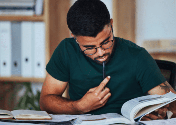 Pessoa estudando para concursos públicos com livros e materiais de preparação para vagas em Câmaras Municipais.