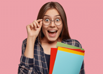 Pessoa surpresa segurando materiais de estudo para concurso público.