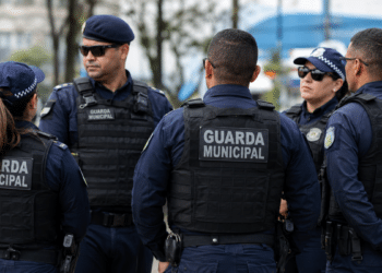 Grupo de guardas municipais fardados durante reunião em espaço urbano.