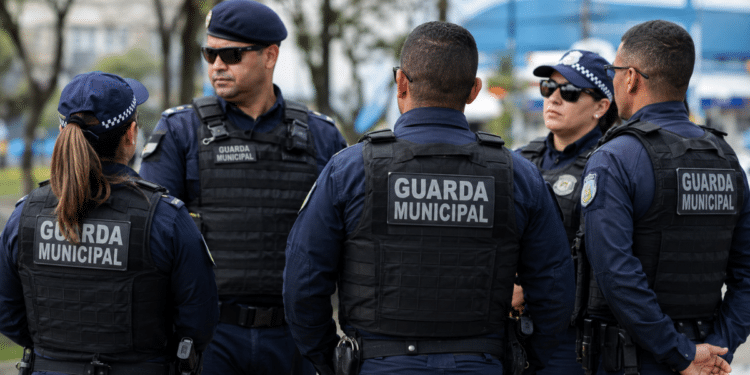 Grupo de guardas municipais fardados durante reunião em espaço urbano.
