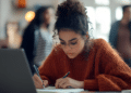 Candidata estudando para concursos públicos com notebook e materiais de preparação para vagas municipais.