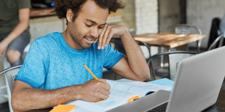 Candidato estuda com notebook e material impresso para concursos de prefeituras com vagas de nível médio.