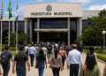 Grupo de pessoas caminhando em direção a uma prefeitura, representando concursos públicos com inscrições abertas em São Paulo e no Rio Grande do Sul.