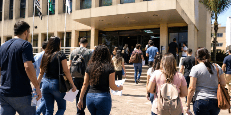 Candidatos caminham em direção a prédio público para participar de concurso municipal em São Paulo.