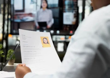 Recrutador avalia currículo com foto durante uma entrevista de emprego.