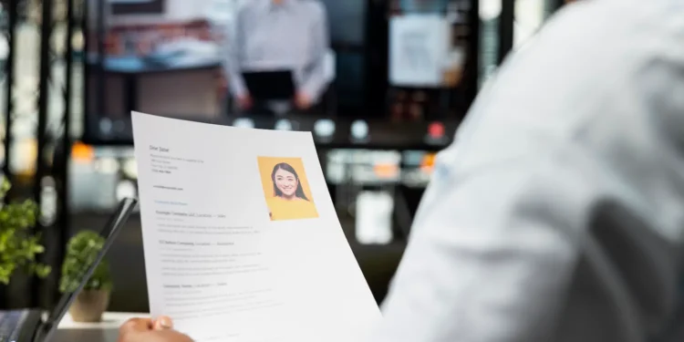 Recrutador avalia currículo com foto durante uma entrevista de emprego.