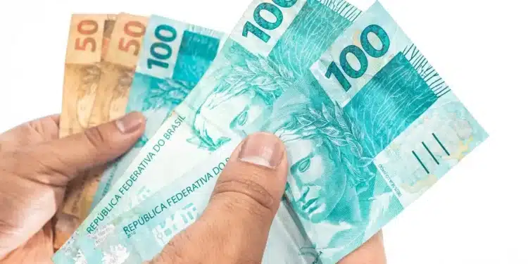 Cédulas de real seguradas por uma pessoa representam o pagamento do lucro do FGTS confirmado pela Caixa para 138,2 milhões de trabalhadores.