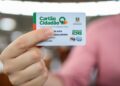 Mão segura o Cartão Cidadão do Devolve ICMS, usado para receber o benefício em 2026