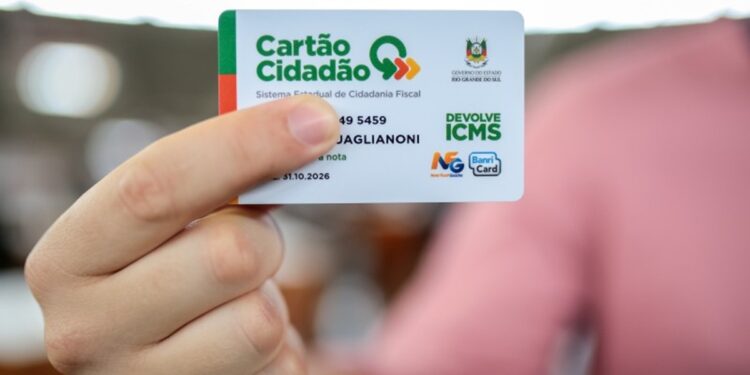 Mão segura o Cartão Cidadão do Devolve ICMS, usado para receber o benefício em 2026