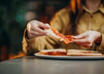 Pessoa pegando uma fatia de pizza, tema ligado à taxa de serviço e aos direitos do consumidor no Dia da Pizza