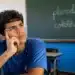 Estudante pensativo em sala de aula, com quadro ao fundo contendo as palavras “plural” e “coletivo” escritas, representando a diferença entre os conceitos da língua portuguesa.