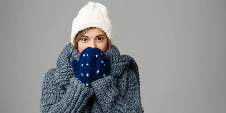 Pessoa agasalhada em ambiente de inverno refletindo sobre a dúvida gramatical se a palavra “frio” possui forma no diminutivo na língua portuguesa.