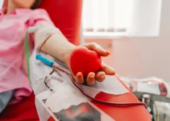 Pessoa realizando doação de sangue com bolsa coletora durante procedimento em banco de sangue.