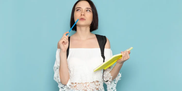 Estudante pensativa segurando caderno e caneta, ilustrando a dúvida sobre a grafia correta entre bagagem e bagajem.