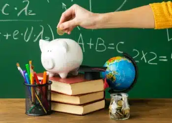 Cofrinho, livros e materiais escolares representam a inclusão da educação financeira nas salas de aula brasileiras.