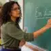Professora escrevendo a expressão “Em diante” no quadro durante uma aula de português, representando a dúvida sobre o uso correto de “em diante” ou “endiante”.