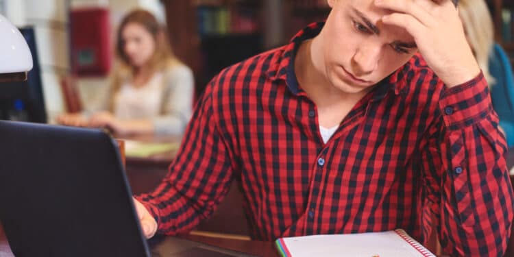 Estudante preocupado diante do notebook, ligado à escolha do curso superior por motivos financeiros