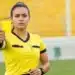 Mulher em campo segurando cartão amarelo durante partida esportiva, representando o feminino correto de árbitro.