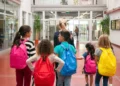 Estudantes com mochilas caminham dentro da escola.