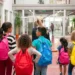 Estudantes com mochilas caminham dentro da escola.