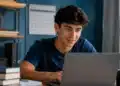 Jovem estudante utilizando notebook em ambiente de estudos, representando a inscrição no Fies 2026 do segundo semestre.
