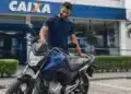 Homem ao lado de uma motocicleta nova em frente a uma agência da Caixa, representando o financiamento de motos pelo Move Brasil.