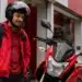 Entregador brasileiro ao lado de moto nova em concessionária, representando o financiamento pelo programa Move Brasil.