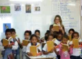 Professora conduz atividade de leitura com estudantes em sala de aula durante iniciativa de formação educacional.