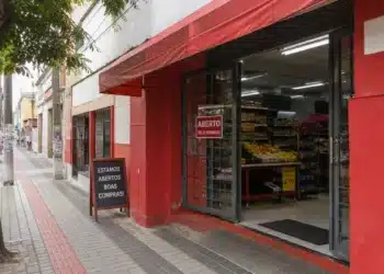 Fachada de comércio aberto em feriado com placa de funcionamento na entrada