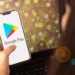 Pessoa segurando celular com aplicativo Google Play aberto, representando o passo a passo para solicitar reembolso de aplicativos e jogos comprados na plataforma.