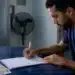 Jovem brasileiro assina documentos relacionados ao Fies Empreendedor, ilustrando a cobrança de juros durante o período de carência.