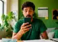 Homem olhando para o celular com expressão de surpresa, representando a consulta ao lote especial de restituição do Imposto de Renda.