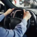 Motorista segura o volante de um carro enquanto avalia financiamento pelo Programa Move Brasil.