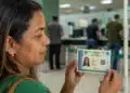 Mulher segura a nova Carteira de Identidade Nacional, representando o atendimento durante o mutirão para a emissão do documento no dia 30 de julho.