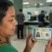 Mulher segura a nova Carteira de Identidade Nacional, representando o atendimento durante o mutirão para a emissão do documento no dia 31 de julho.