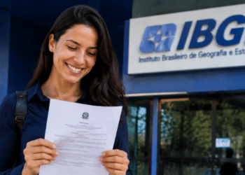 Pessoa segurando documento oficial em frente à sede do IBGE, representando nomeações de classificados do CNU 2024..