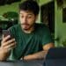 Homem olhando o celular à mesa, com um tablet à frente e um carro ao fundo, cena que representa as novidades do WhatsApp para o telefone, o tablet e o carro.