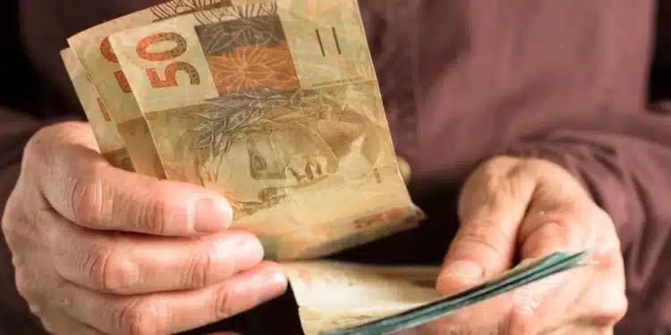 Pessoa segura cédulas de real, representando o pagamento do BPC previsto para agosto de 2026.