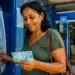 Mulher retirando o pagamento de benefício do INSS em caixa eletrônico de uma agência bancária, representando os depósitos referentes a julho.