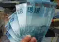 Notas de dinheiro em reais em destaque, representando pagamentos do INSS de até R$ 8.475,55, nos dias 2 e 3 de julho de 2026.