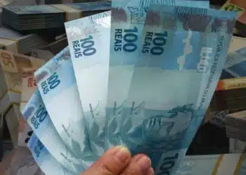 Notas de dinheiro em reais em destaque, representando pagamentos do INSS de até R$ 8.475,55, nos dias 2 e 3 de julho de 2026.