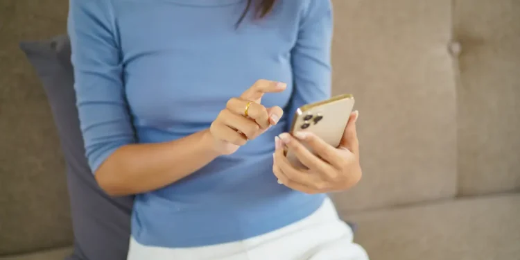 Mulher utilizando celular para acompanhar transferência automática de pensão alimentícia pelo Pix Pensão.